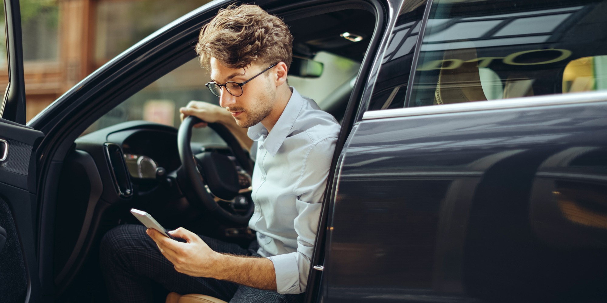 Man checks smartphone before driving his car