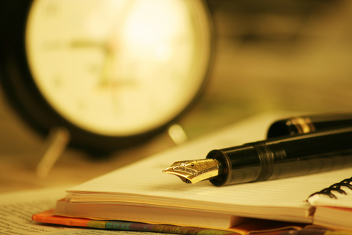 Fountain Pen on Open Notebook Page with Blurred Out Clock in Background