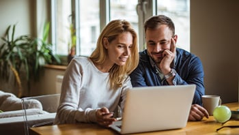 Woman and Man Sitting at Desk with Laptop
