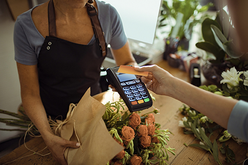 Merchant Wrapping Bouquet of Flowers while Customer Uses Touch-Free Credit Card
