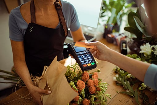 Merchant Wrapping Bouquet of Flowers while Customer Uses Touch-Free Credit Card
