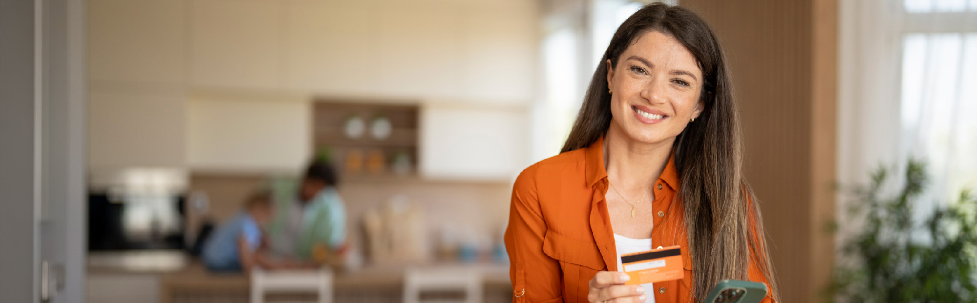 Woman Smiling and Holding Debit Card on Sunny Day Indoors