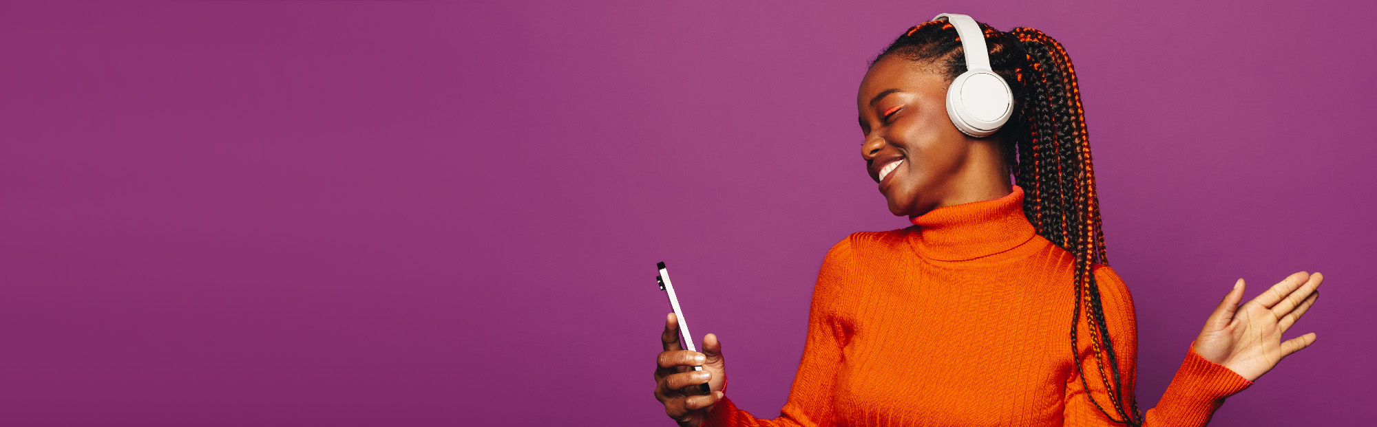 Young Woman Dancing with Headphones On Against Purple Background