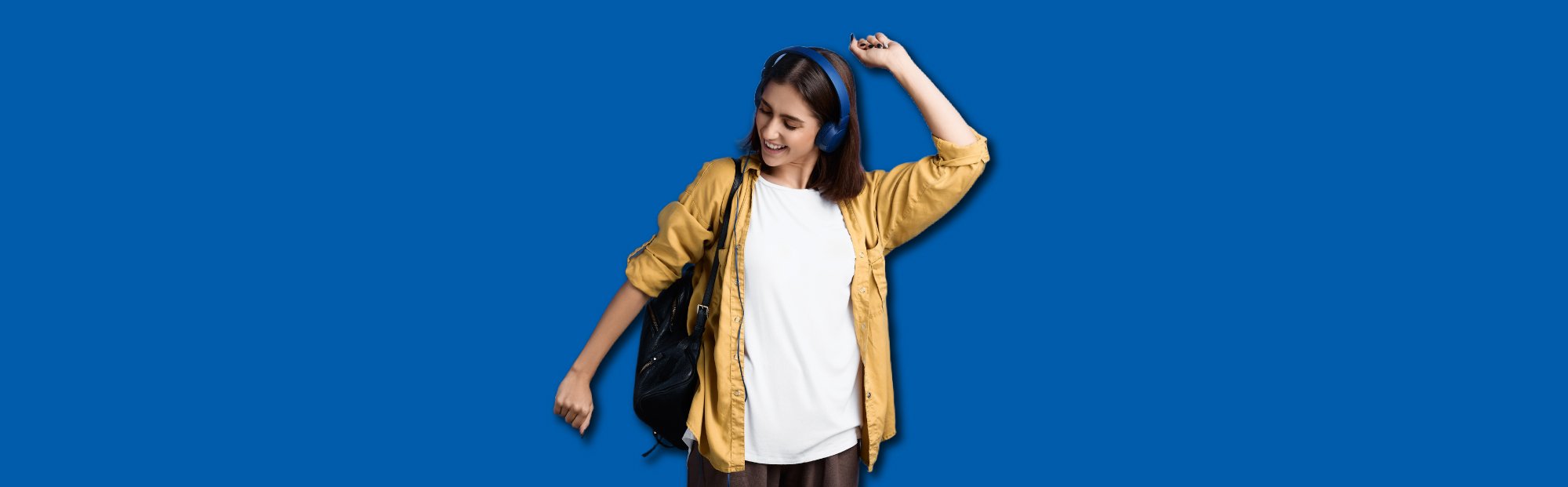 Young Lady Dancing while Wearing Blue Headphones in Front of Blue Background