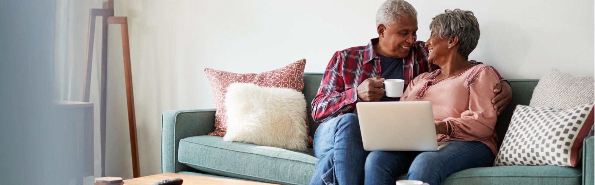 Senior Couple Using Laptop and Drinking Coffee while Sitting on Sofa