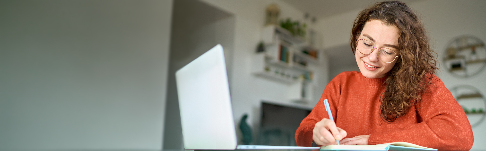 Woman Using Laptop and Taking Notes