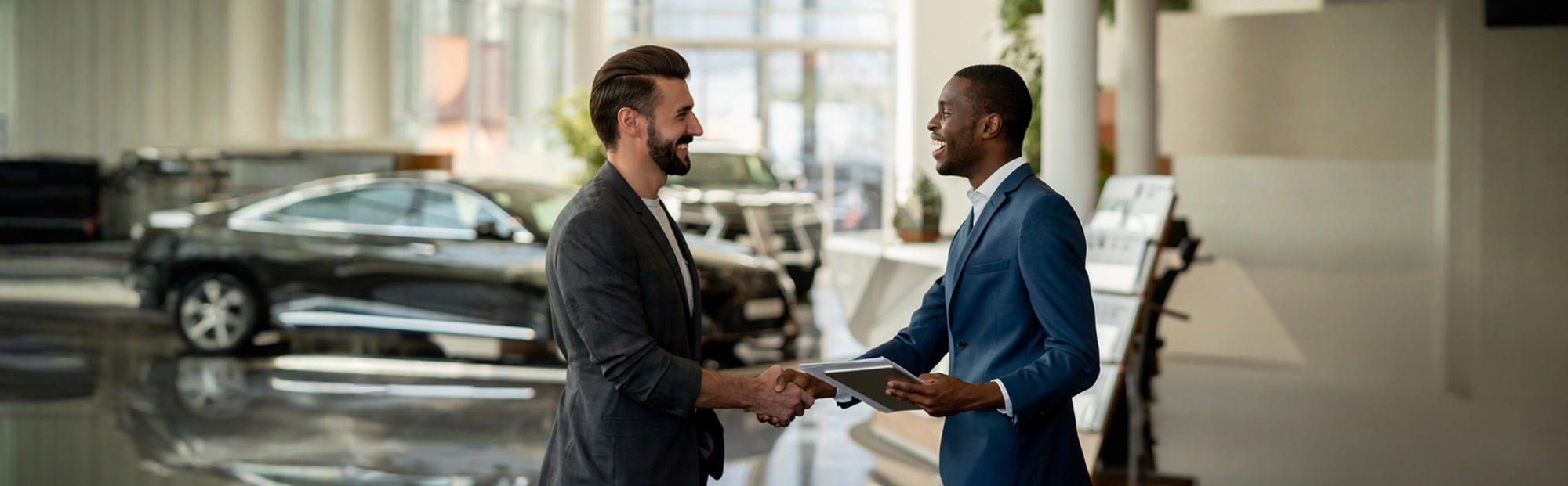 Driver and dealer shake hands at car dealership