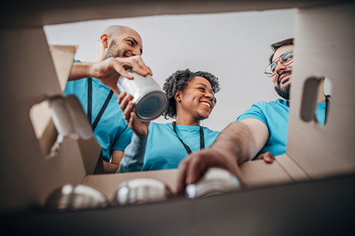 From the Inside of a Canned Food Box Looking Up at Smiling Volunteers