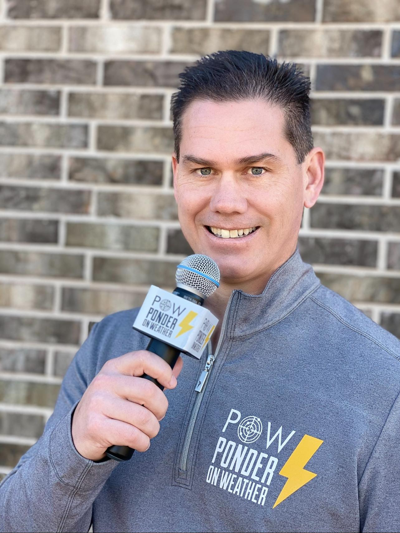 POW Profile Pic POW Representative with Microphone in Front of Brick Building
