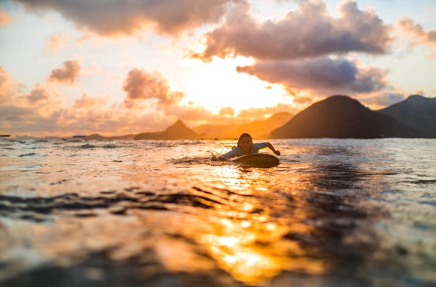 Girl Paddling on Surfboard at Sunset