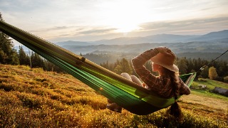 Woman in Hammock Overlooking Valley at Sunset
