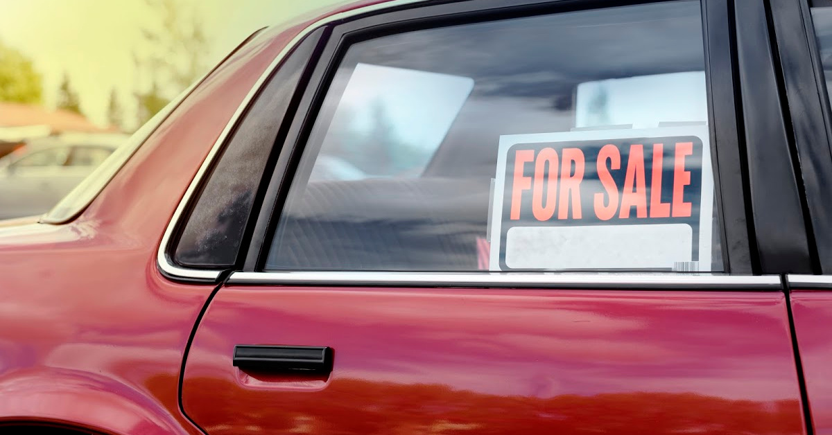 Red Car with "For Sale" Sign in Passenger Side Window