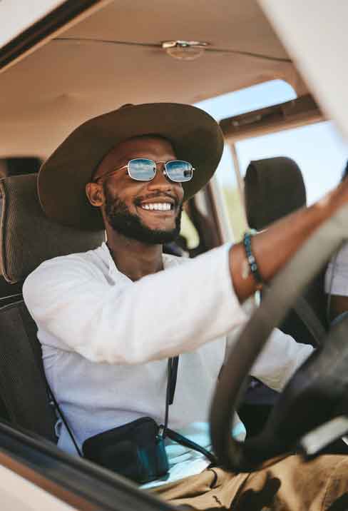Young Man in Driver's Seat of Car, Wearing Sunglasses and Smiling