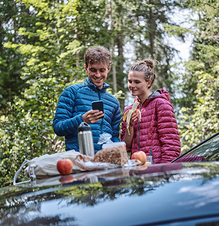 Man and Woman Having Picnic on Hood of Car in Forest